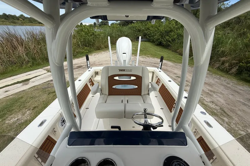 Slide: The Image of 2026 Pathfinder 2700 Open boat interior with steering wheel and seating, near a grassy shoreline. - 21