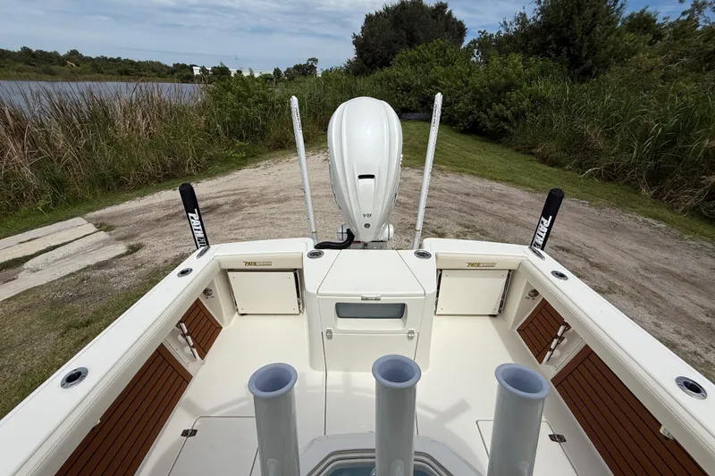 Slide: The Image of 2026 Pathfinder 2700 Open boat with outboard motor, docked near lush greenery. - 22