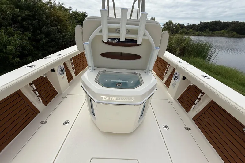 Slide: The Image of 2026 Pathfinder 2700 Open boat interior with fishing rod holders and livewell, near a serene lake. - 25