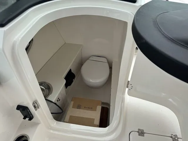 Slide: The Image of Interior of 2025 Robalo R257 boat showing compact marine toilet and storage space. - 7