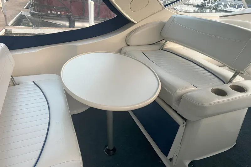 Slide: The Image of 2003 Bayliner 285 boat interior with white seating and round table. - 12