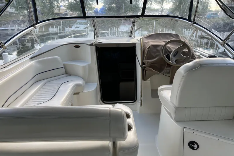 Slide: The Image of Interior of 2003 Bayliner 285 boat with white seating and steering wheel. - 13