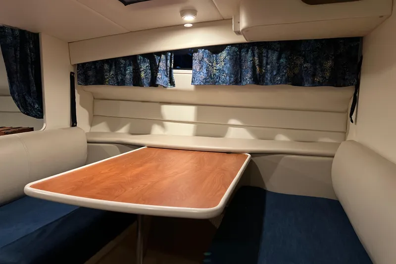 Slide: The Image of Interior of 2003 Bayliner 285 boat with wood table and blue curtains. - 17