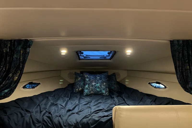 Slide: The Image of 2003 Bayliner 285 cabin interior with cozy bedding and ambient lighting. - 18