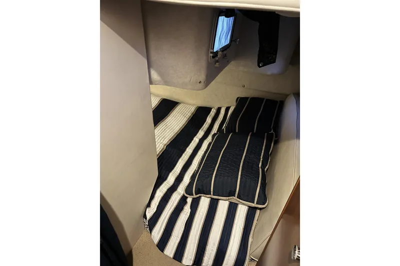 Slide: The Image of Interior cabin of 2003 Bayliner 285 with striped bedding and small window. - 19