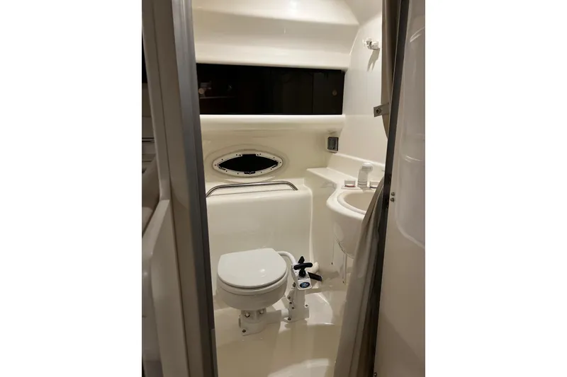 Slide: The Image of 2003 Bayliner 285 boat bathroom interior with toilet, sink, and porthole window. - 21