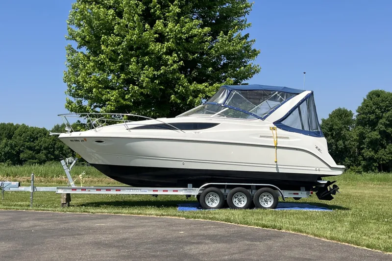 Slide: The Image of 2003 Bayliner 285 boat on trailer, parked outdoors with trees in background. - 5