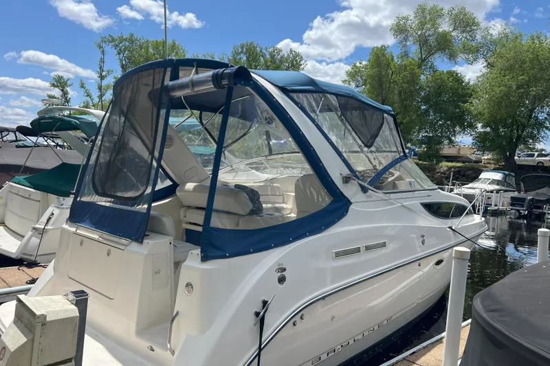 Slide: The Image of 2003 Bayliner 285 boat docked, featuring blue canopy and clear windows, surrounded by trees and water. - 8