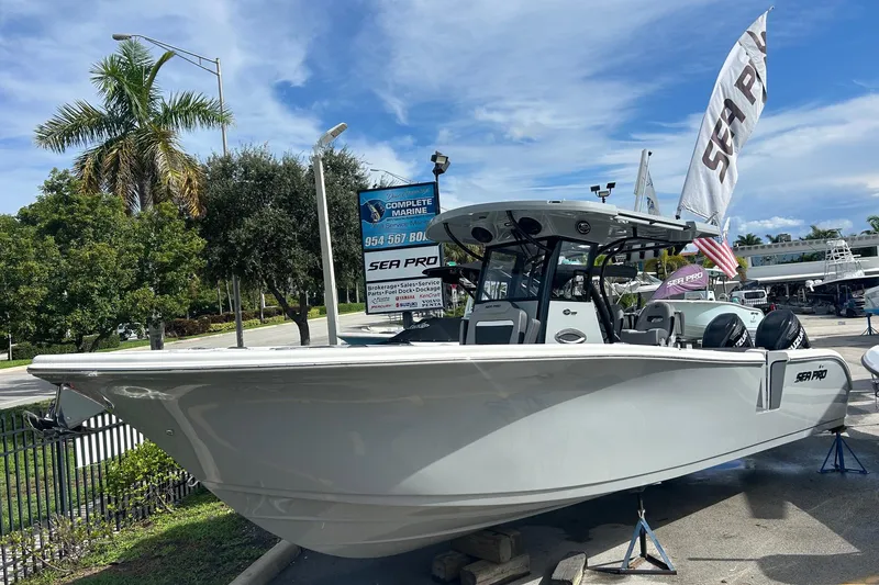 The Image of 2026 Sea Pro 292 DLX boat displayed outdoors with palm trees and flags. - 0