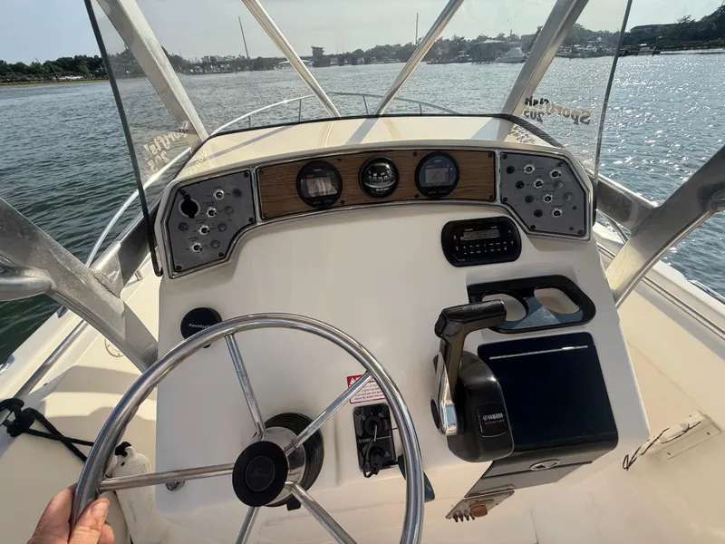 Slide: The Image of 2009 Scout 205 Sportfish boat dashboard with steering wheel and controls on the water. - 19