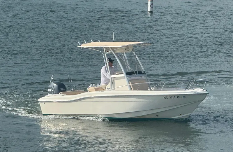 Slide: The Image of 2009 Scout 205 Sportfish boat cruising on water with a person at the helm. - 2