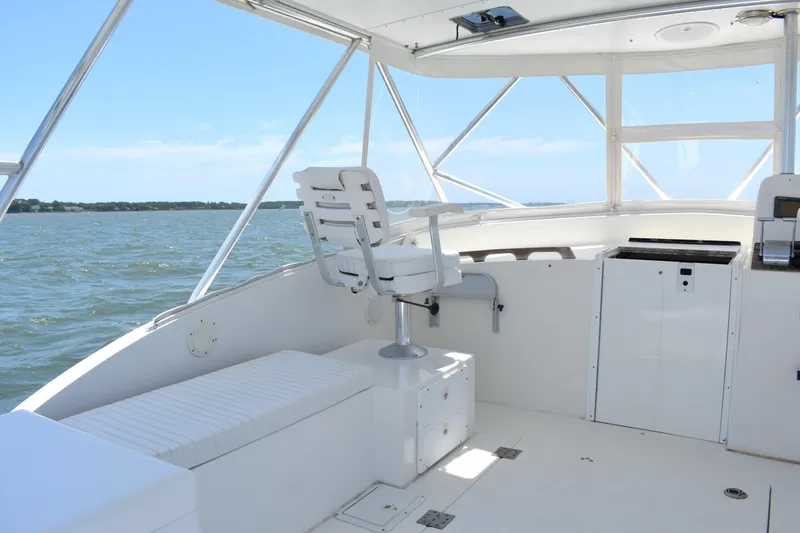 Slide: The Image of 2004 Judge 34 Express boat interior with helm seat, white cabinetry, and ocean view. - 19