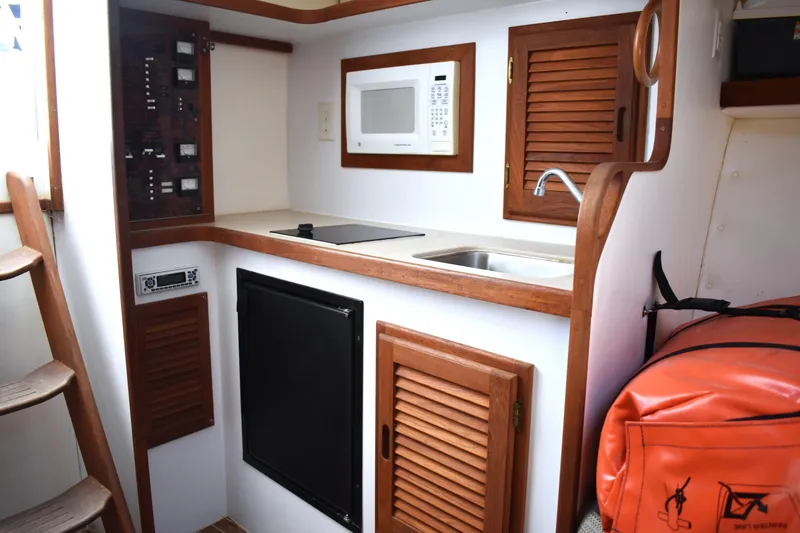 Slide: The Image of 2004 Judge 34 Express boat kitchen with microwave, sink, and storage cabinets. - 25