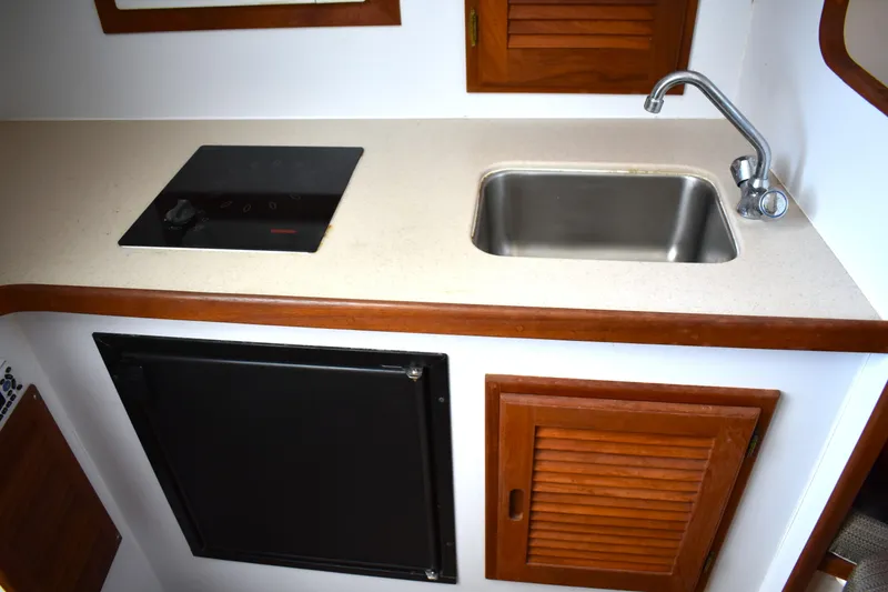 Slide: The Image of 2004 Judge 34 Express boat kitchen with sink, stove, and wooden cabinets. - 29