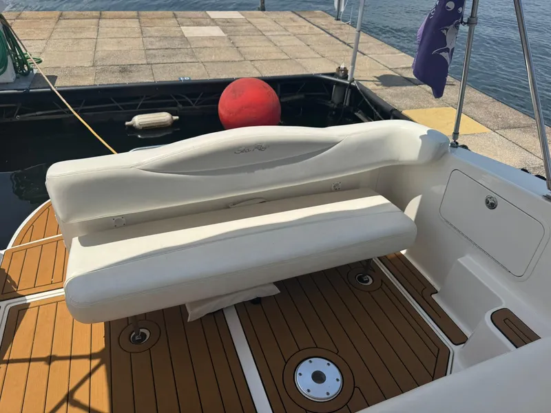 Slide: The Image of 2004 Sea Ray 280 Sundancer boat interior with white seating and teak flooring at a dock. - 10