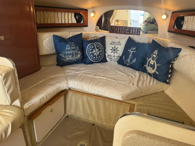 Slide: The Image of Interior of 2004 Sea Ray 280 Sundancer with nautical-themed cushions and cozy seating. - 15