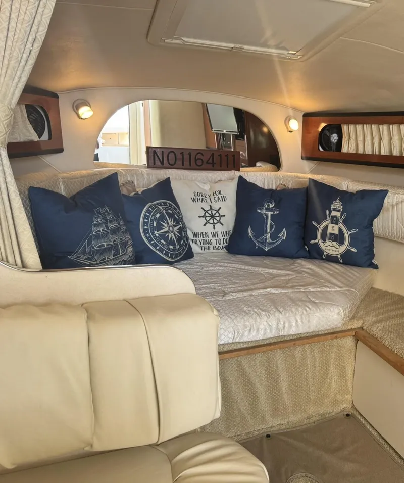 Slide: The Image of Interior of 2004 Sea Ray 280 Sundancer with nautical-themed pillows and cozy seating. - 16