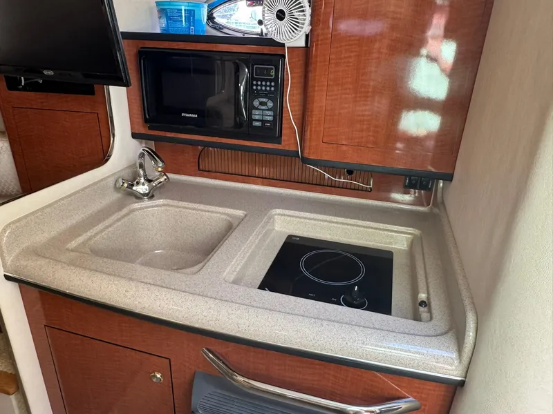 Slide: The Image of 2004 Sea Ray 280 Sundancer galley with sink, microwave, and stovetop. - 19