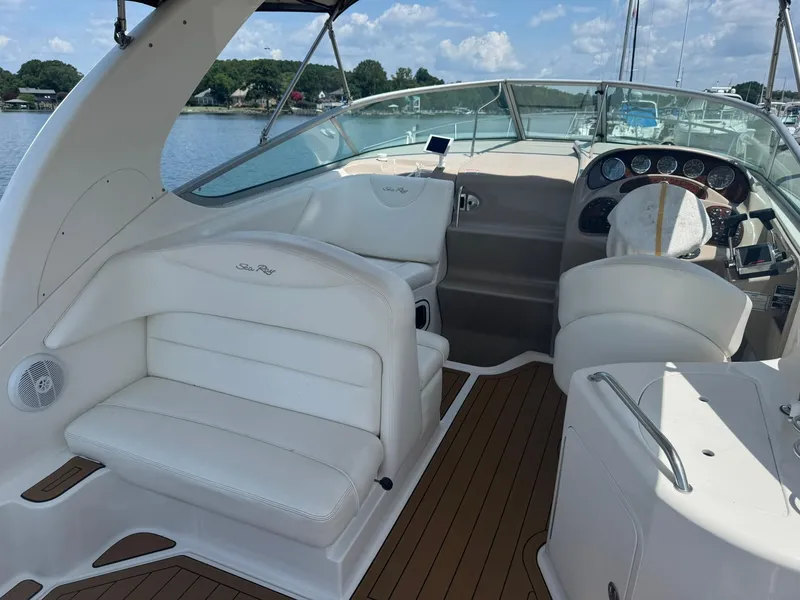 Slide: The Image of 2004 Sea Ray 280 Sundancer boat interior with white seating and wooden flooring. - 7