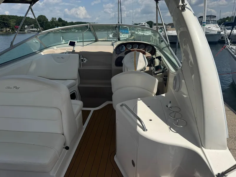 Slide: The Image of 2004 Sea Ray 280 Sundancer boat interior with helm, white seating, and wood flooring. - 8