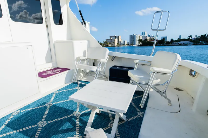 Slide: The Image of Boat deck with white chairs and table, blue patterned rug, city skyline in background. - 21