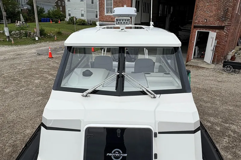 Slide: The Image of 2020 Protector 310 Targa boat, front view, parked near brick building. - 12