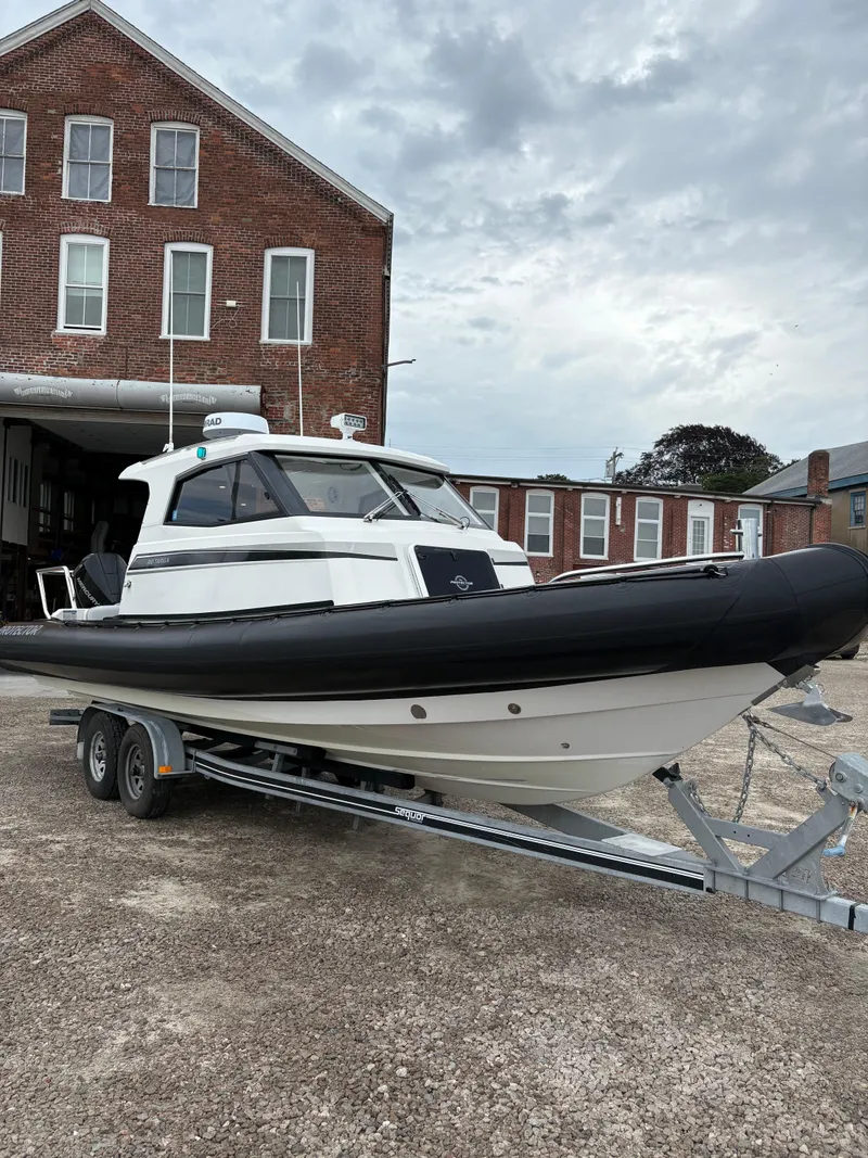 Slide: The Image of 2020 Protector 310 Targa boat on trailer, parked outside brick building. - 8