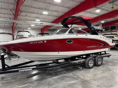 Slide: The Image of 2009 Chaparral 264 Sunesta boat in a showroom, red and white exterior, on a trailer. - 1