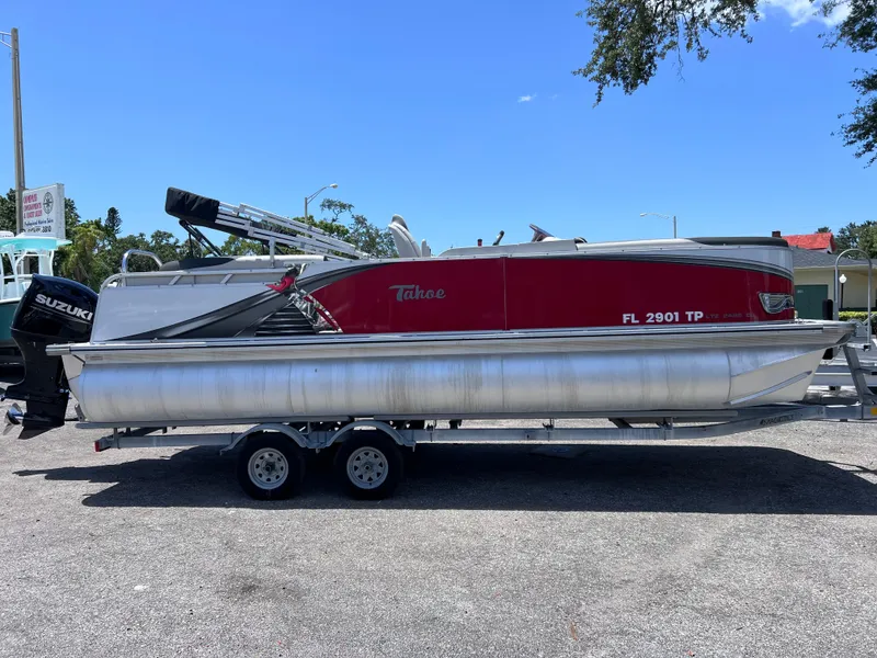 The Image of 2022 Tahoe Pontoon LTZ 2485 EL on trailer, red and silver design, parked outdoors. - 0