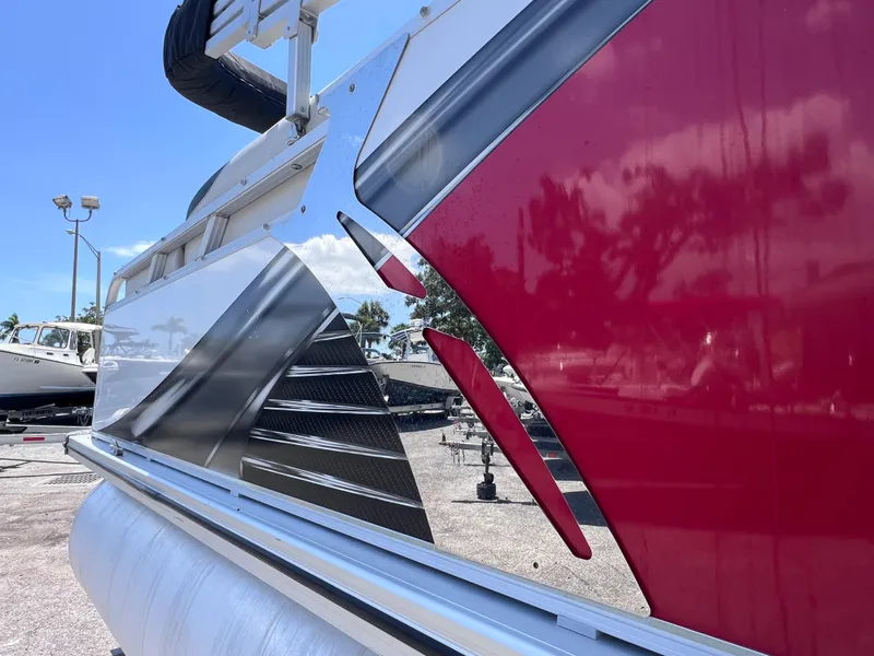 Slide: The Image of 2022 Tahoe Pontoon LTZ 2485 EL with sleek red and silver design, docked outdoors. - 12