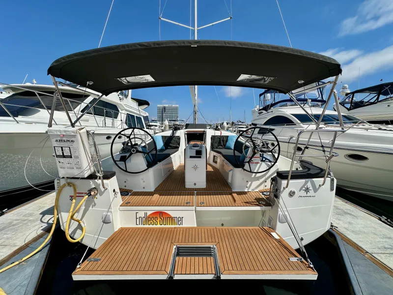 Slide: The Image of 2024 Jeanneau Sun Odyssey 410 sailboat docked, featuring dual steering wheels and teak deck. - 11