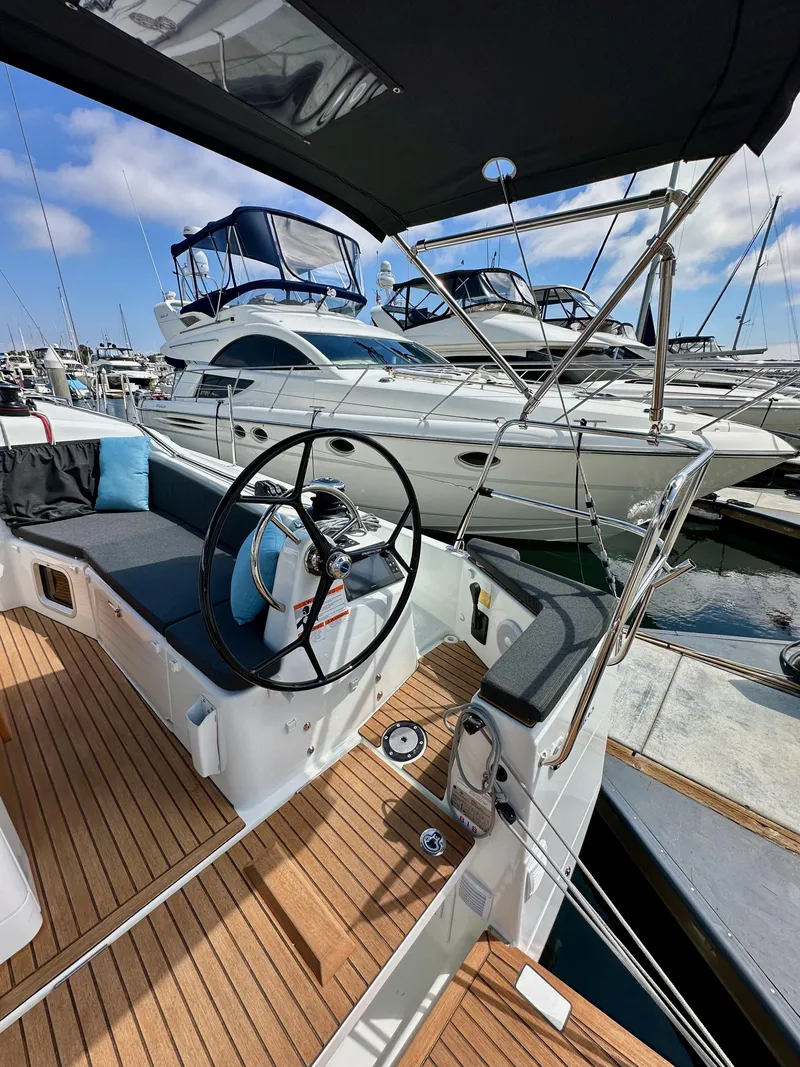 Slide: The Image of 2024 Jeanneau Sun Odyssey 410 sailboat cockpit with steering wheel, docked at marina. - 15