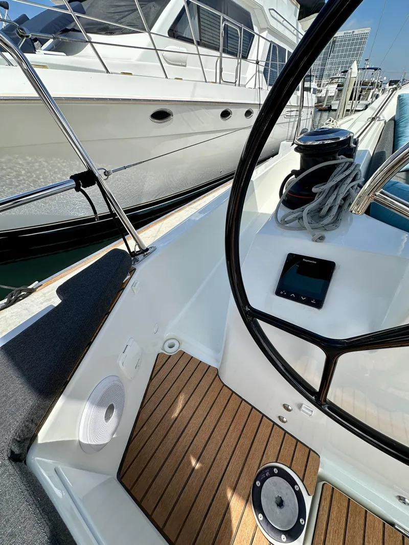 Slide: The Image of 2024 Jeanneau Sun Odyssey 410 cockpit with steering wheel, wooden deck, and navigation equipment. - 16