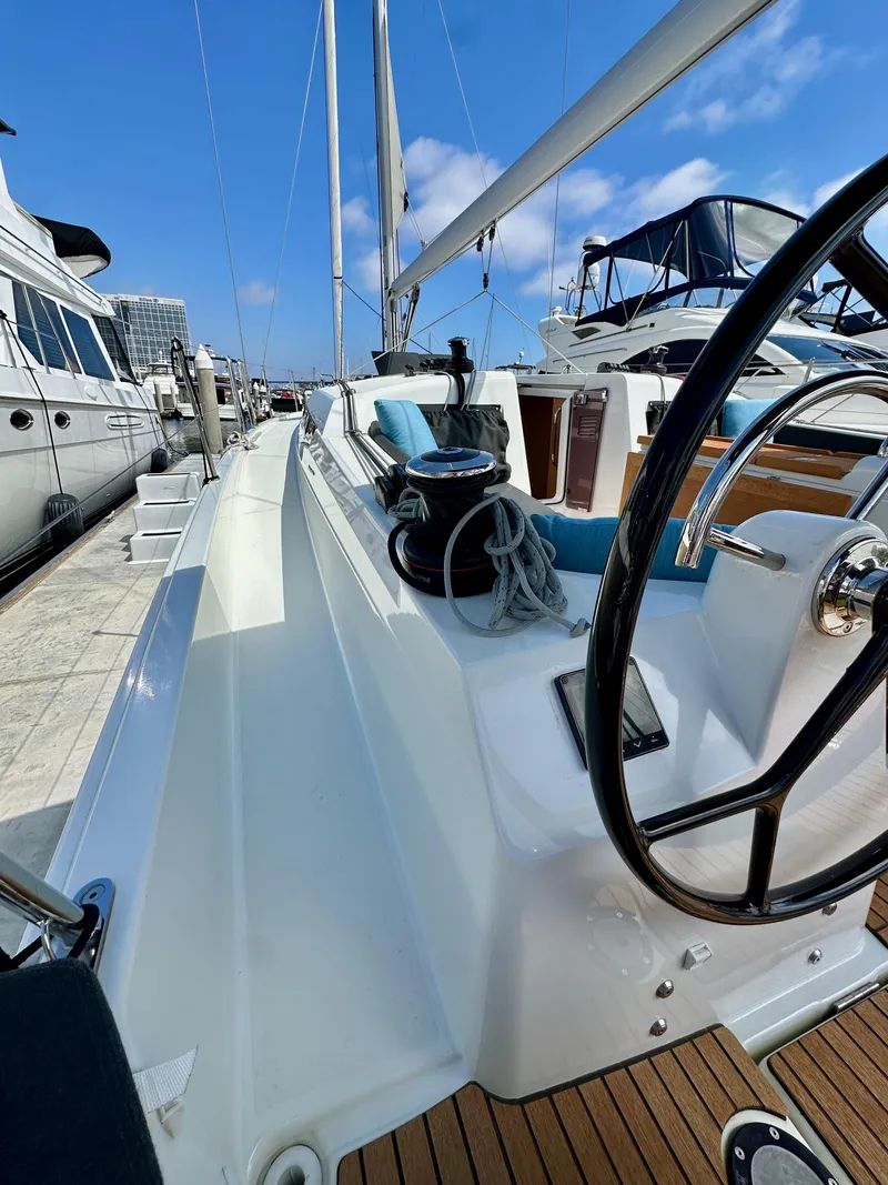 Slide: The Image of 2024 Jeanneau Sun Odyssey 410 sailboat docked, showcasing deck and steering wheel. - 17