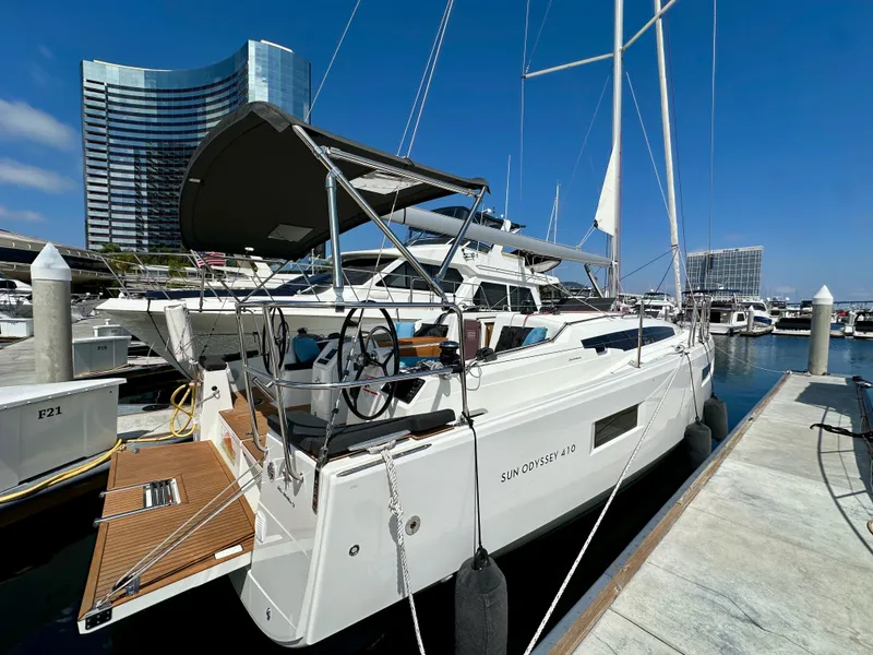 Slide: The Image of 2024 Jeanneau Sun Odyssey 410 yacht docked at marina under clear blue sky. - 2
