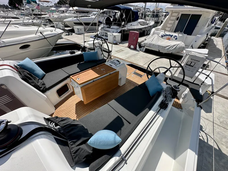 Slide: The Image of 2024 Jeanneau Sun Odyssey 410 yacht cockpit with seating, cushions, and dual steering wheels at marina. - 39