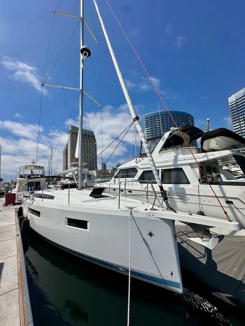 Slide: The Image of 2024 Jeanneau Sun Odyssey 410 sailboat docked at marina, city skyline in background. - 4