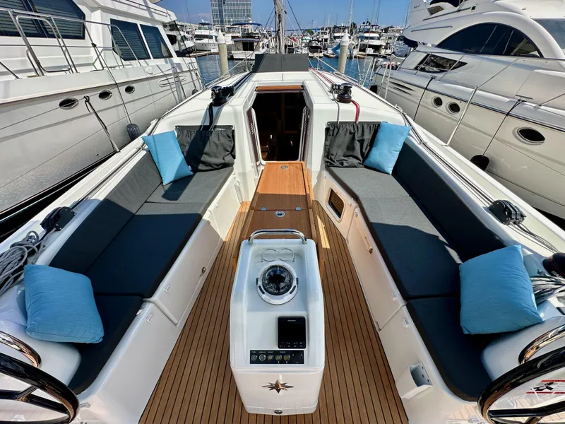 Slide: The Image of 2024 Jeanneau Sun Odyssey 410 yacht deck with seating, cushions, and steering wheel in marina. - 40