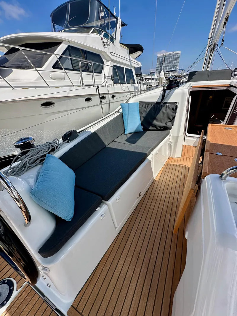 Slide: The Image of 2024 Jeanneau Sun Odyssey 410 yacht deck with cushioned seating and wooden flooring. - 41