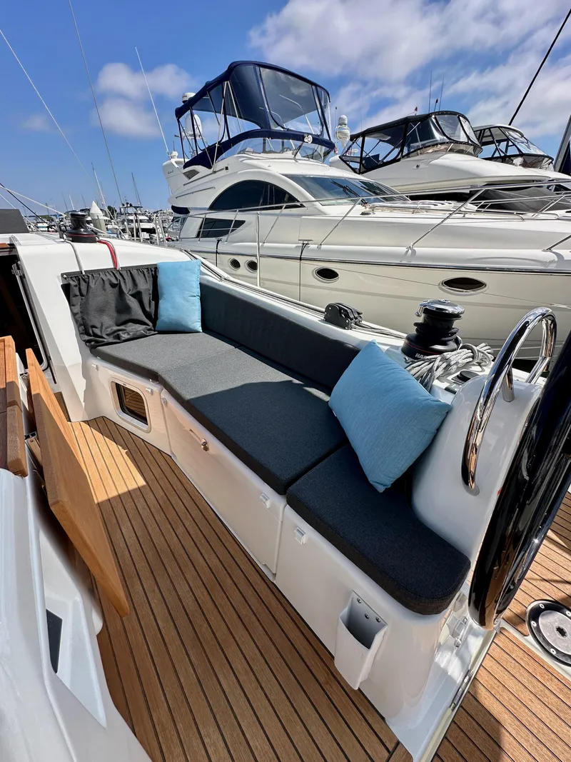 Slide: The Image of 2024 Jeanneau Sun Odyssey 410 yacht cockpit with cushioned seating and wooden deck. - 42