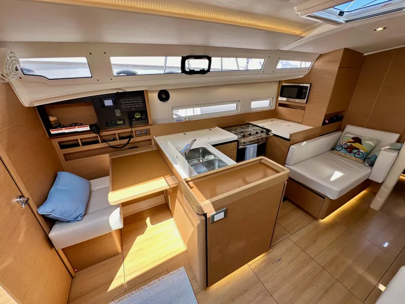 Slide: The Image of 2024 Jeanneau Sun Odyssey 410 interior with modern kitchen, seating, and navigation area. - 46