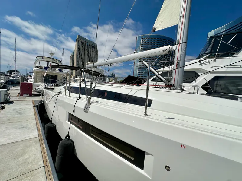 Slide: The Image of 2024 Jeanneau Sun Odyssey 410 yacht docked at marina under clear blue sky. - 8