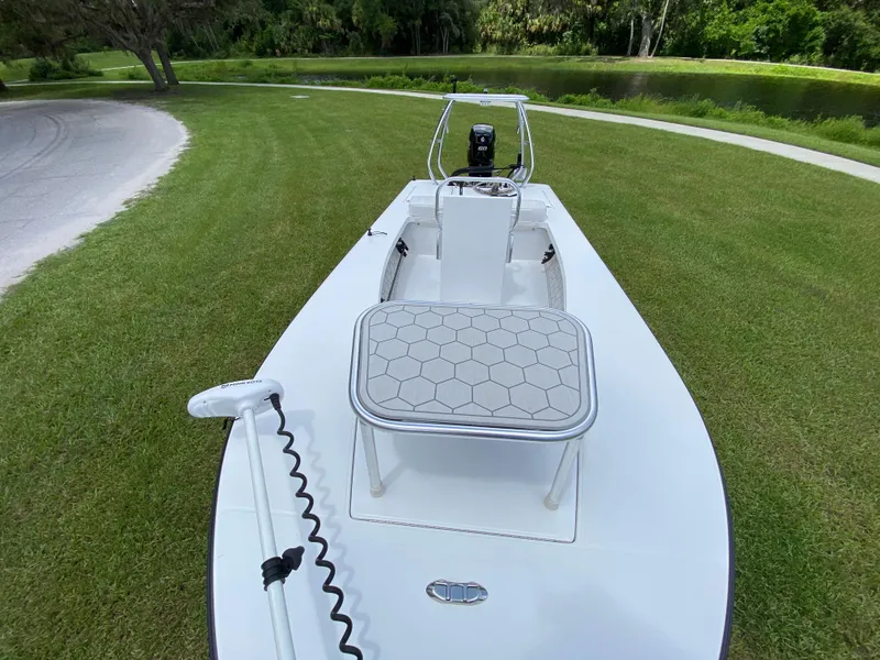 Slide: The Image of 2020 East Cape 18 EVO boat on grass near a pond, showcasing deck and seating. - 27