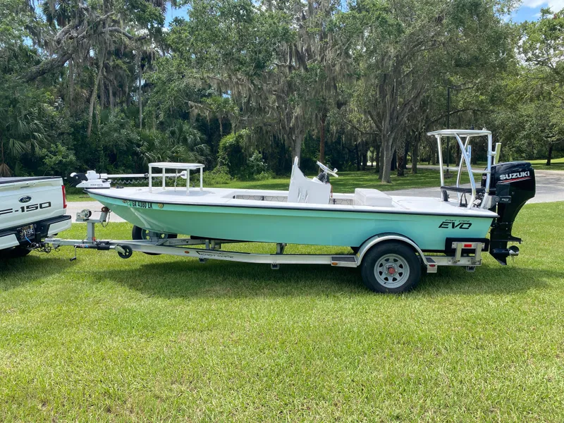 Slide: The Image of 2020 East Cape 18 EVO boat on trailer, parked on grass, with Suzuki outboard motor. - 5