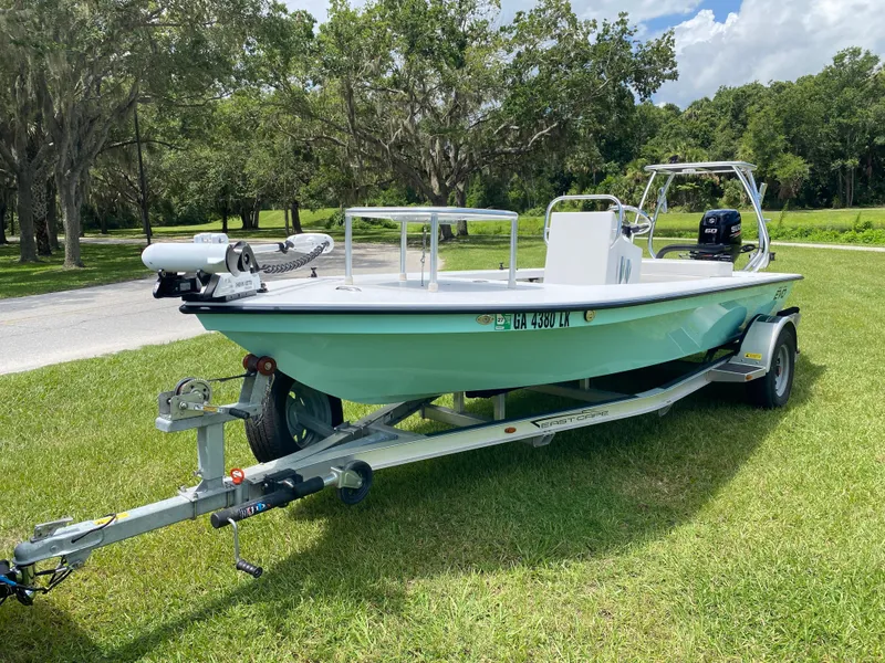 Slide: The Image of 2020 East Cape 18 EVO boat on trailer, parked on grass with trees in background. - 6