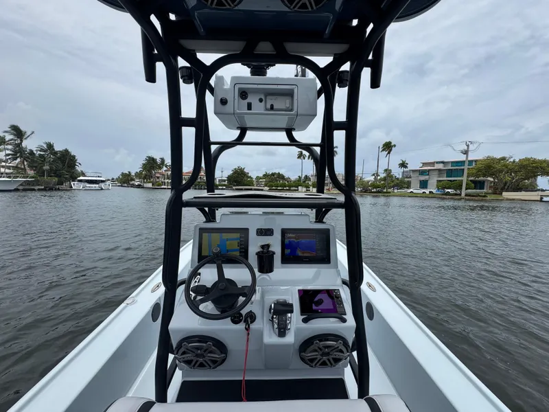 Slide: The Image of 2019 Yellowfin 24 Bay CE boat dashboard with navigation screens on a calm waterway. - 11