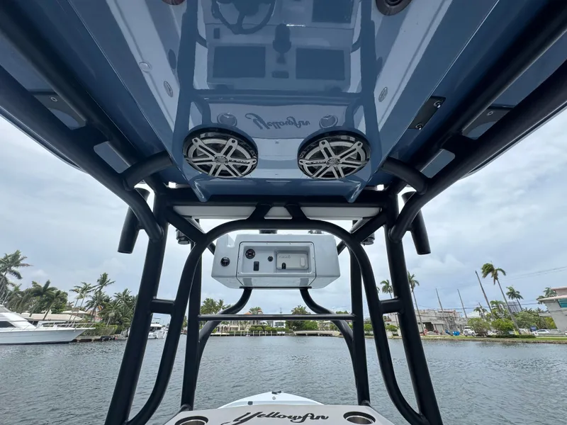 Slide: The Image of 2019 Yellowfin 24 Bay CE boat with speakers and console, docked near palm trees. - 15