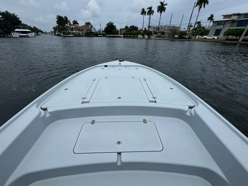 Slide: The Image of 2019 Yellowfin 24 Bay CE boat on calm waterway with palm trees in background. - 24
