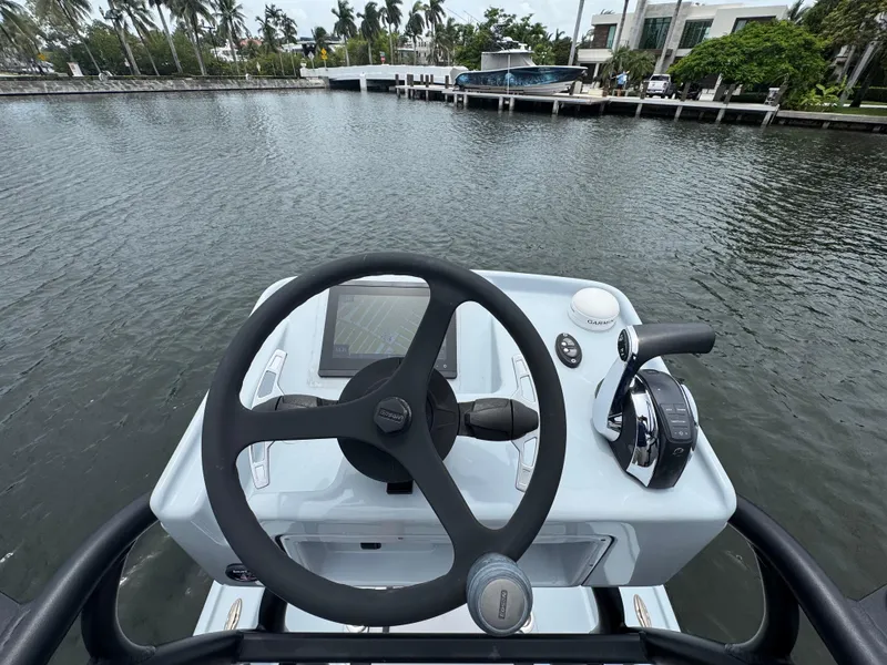 Slide: The Image of 2019 Yellowfin 24 Bay CE boat helm with steering wheel and controls on water. - 30