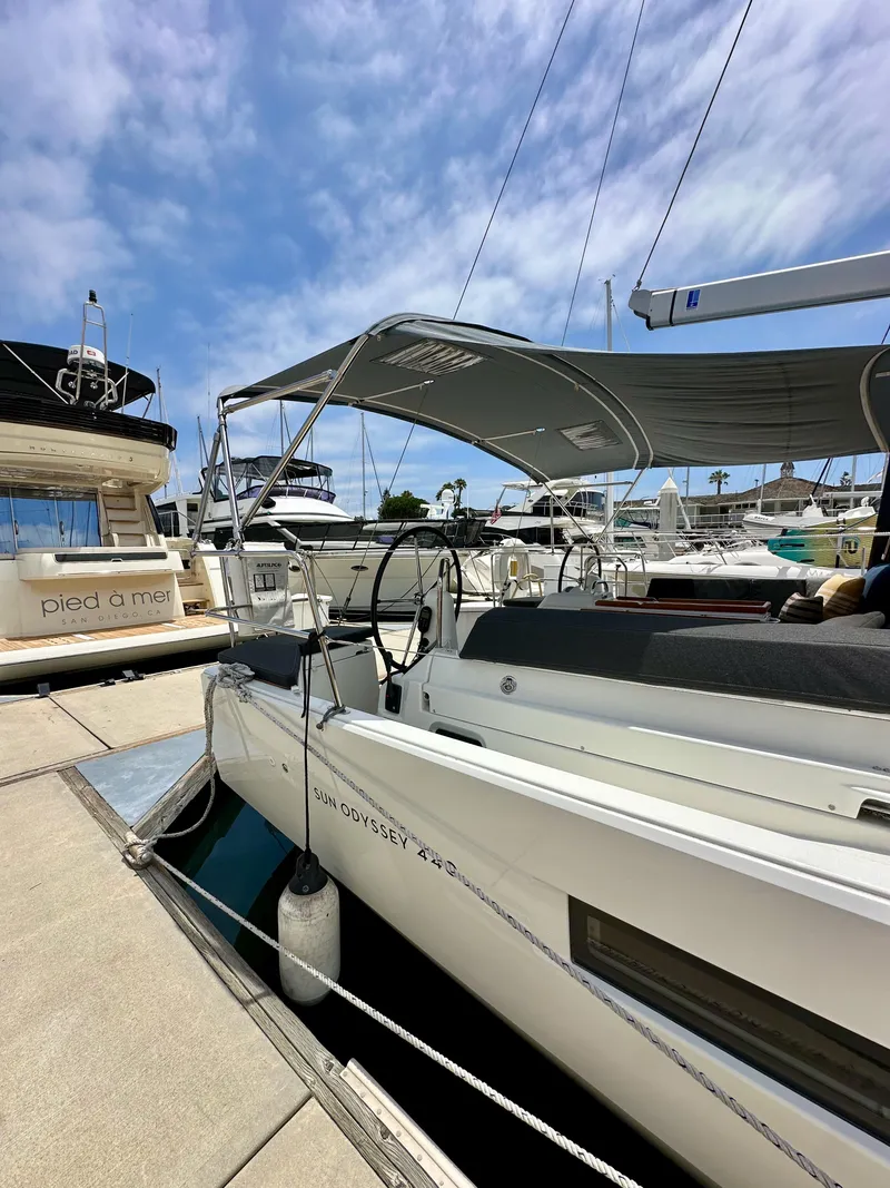 Slide: The Image of 2021 Jeanneau Sun Odyssey 440 docked at marina under clear blue sky. - 12